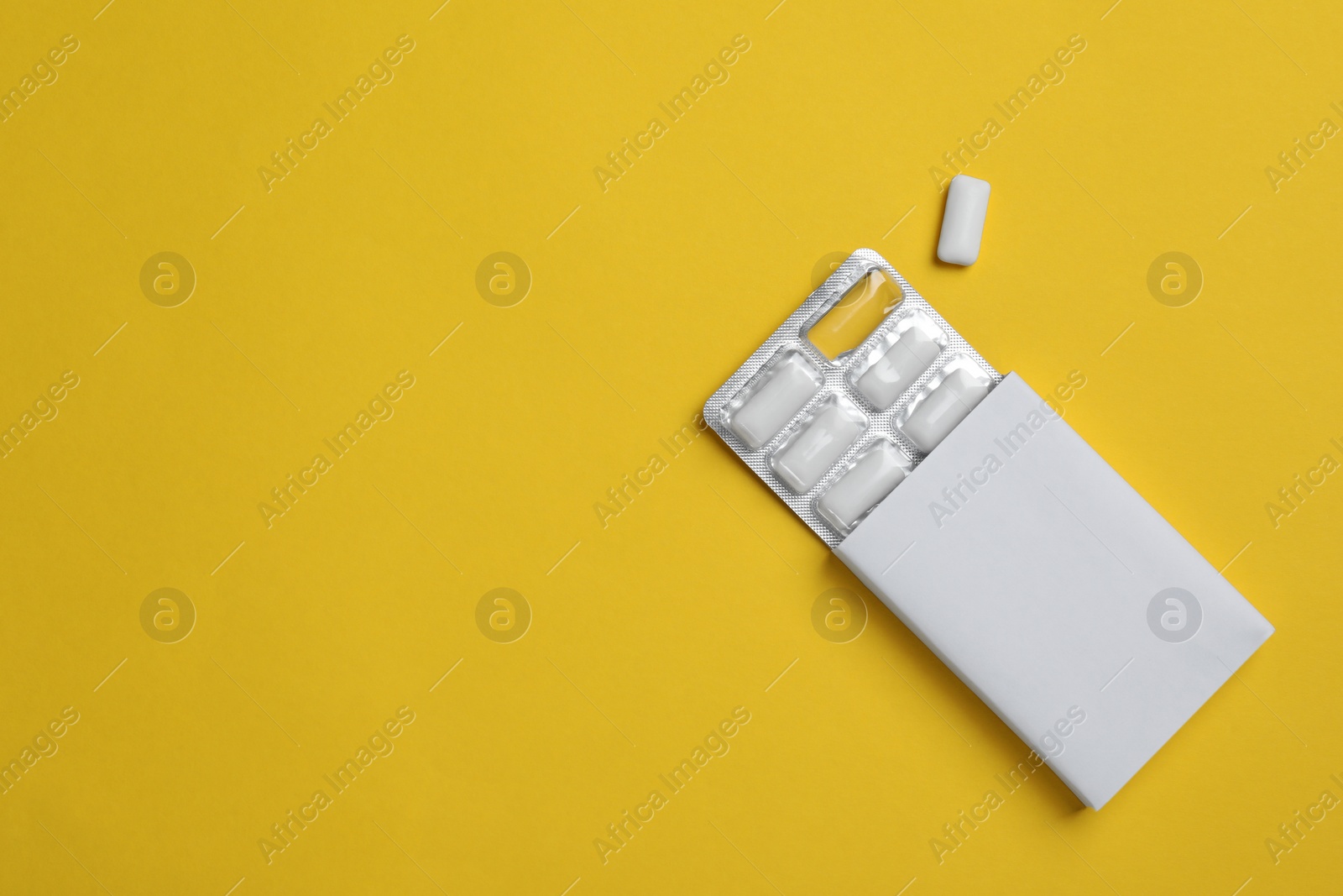 Photo of Pack with tasty chewing gums on yellow background, flat lay. Space for text