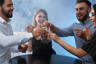 Photo of Young people toasting with Mexican Tequila shots at table in bar
