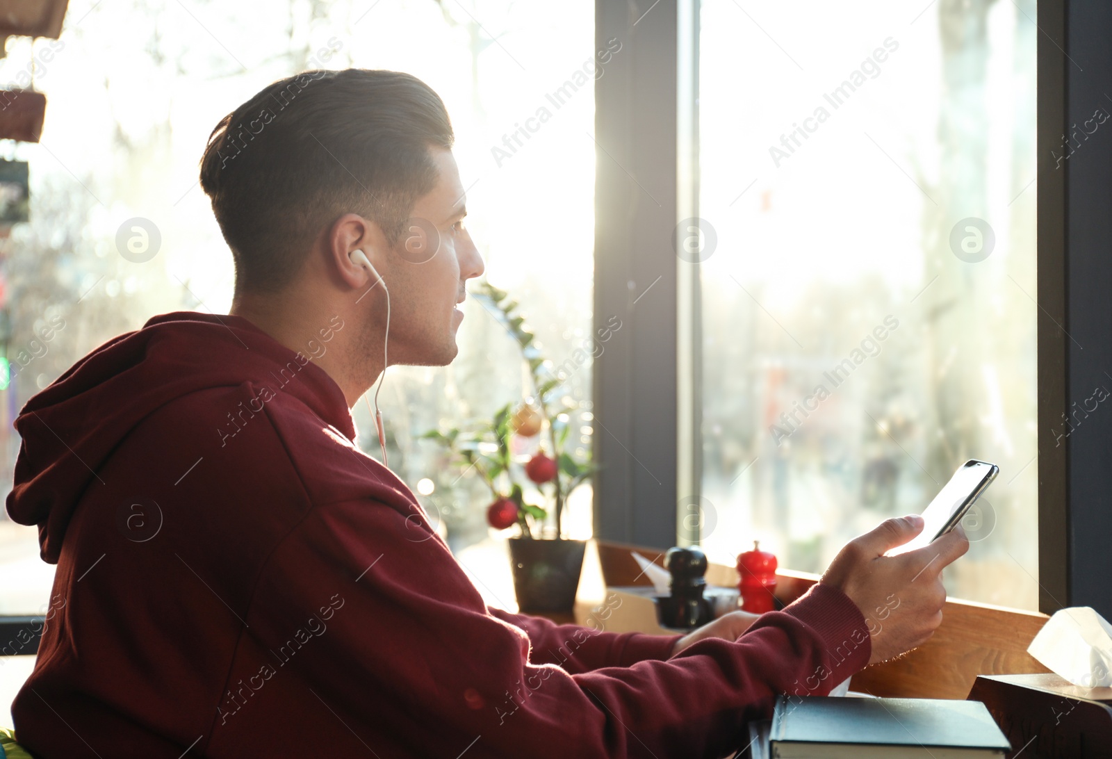 Photo of Man listening to audiobook at table in cafe