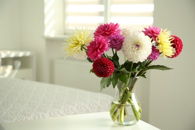 Photo of Bouquet of beautiful Dahlia flowers in vase on white table indoors. Space for text