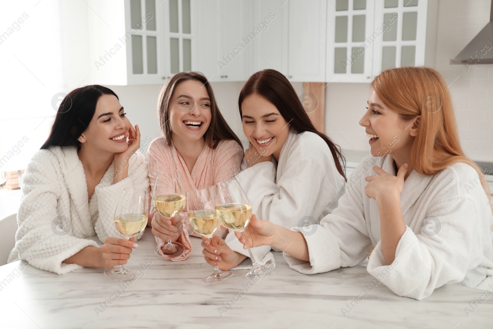 Photo of Beautiful young ladies with glasses of wine in kitchen. Women's Day