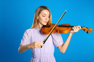 Beautiful woman playing violin on blue background