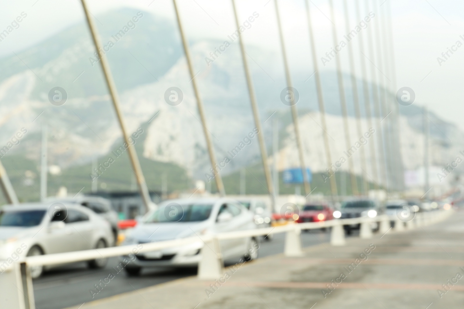 Photo of Blurred view of modern bridge and cars near mountain