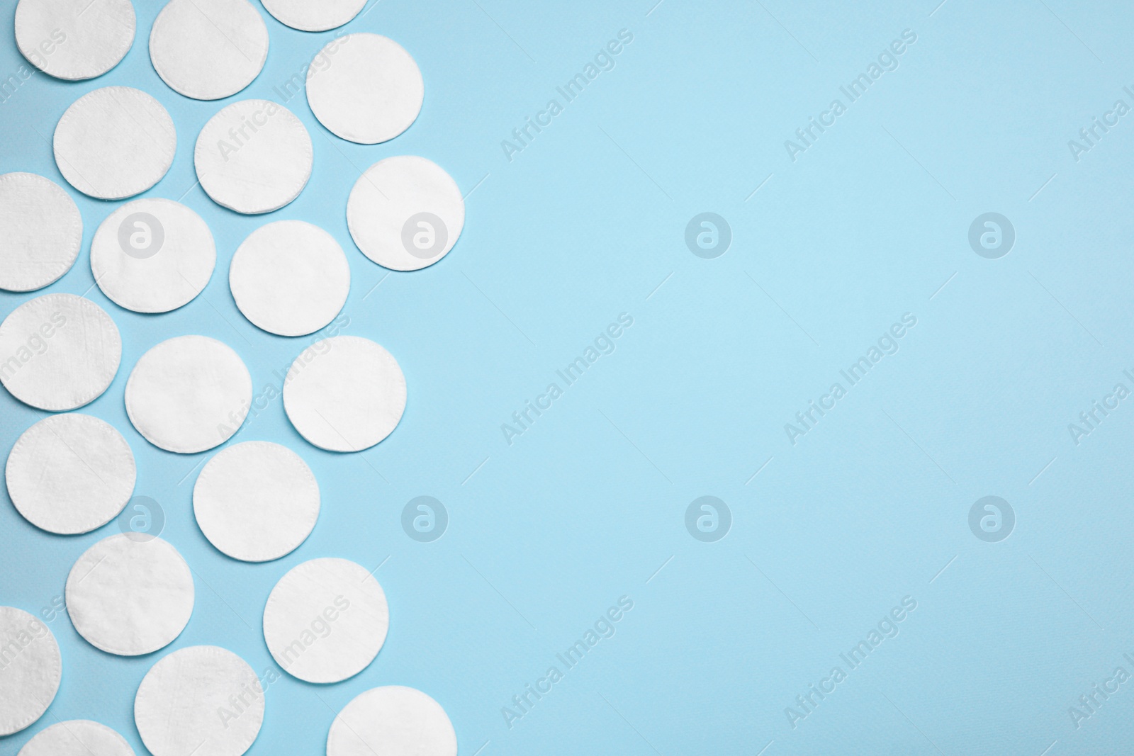 Photo of Many cotton pads on light blue background, flat lay. Space for text