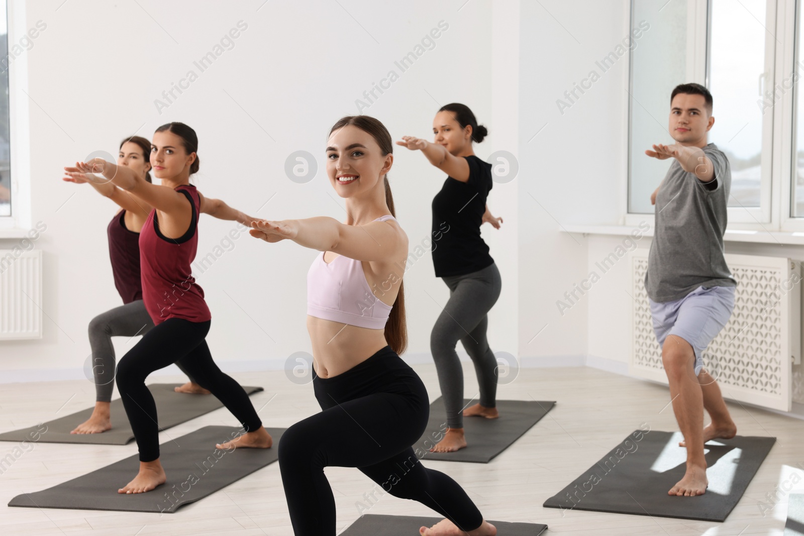 Photo of Group of people practicing yoga on mats indoors