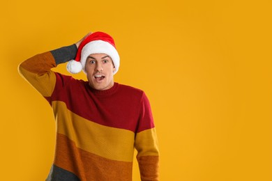 Photo of Excited man in Santa hat on yellow background, space for text. Christmas countdown