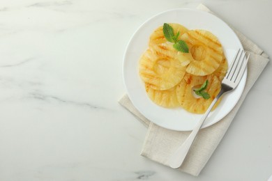 Tasty grilled pineapple slices and mint on white table, top view. Space for text