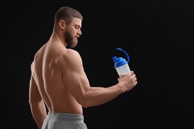 Photo of Young man with muscular body holding shaker of protein on black background, space for text