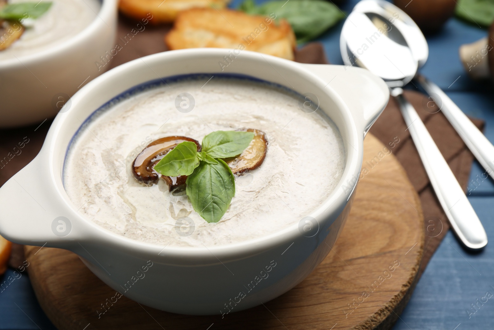 Photo of Fresh homemade mushroom soup served on blue wooden table, closeup