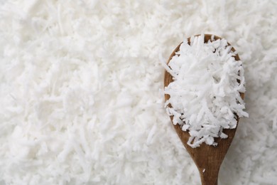 Photo of Fresh coconut flakes and wooden spoon, top view. Space for text