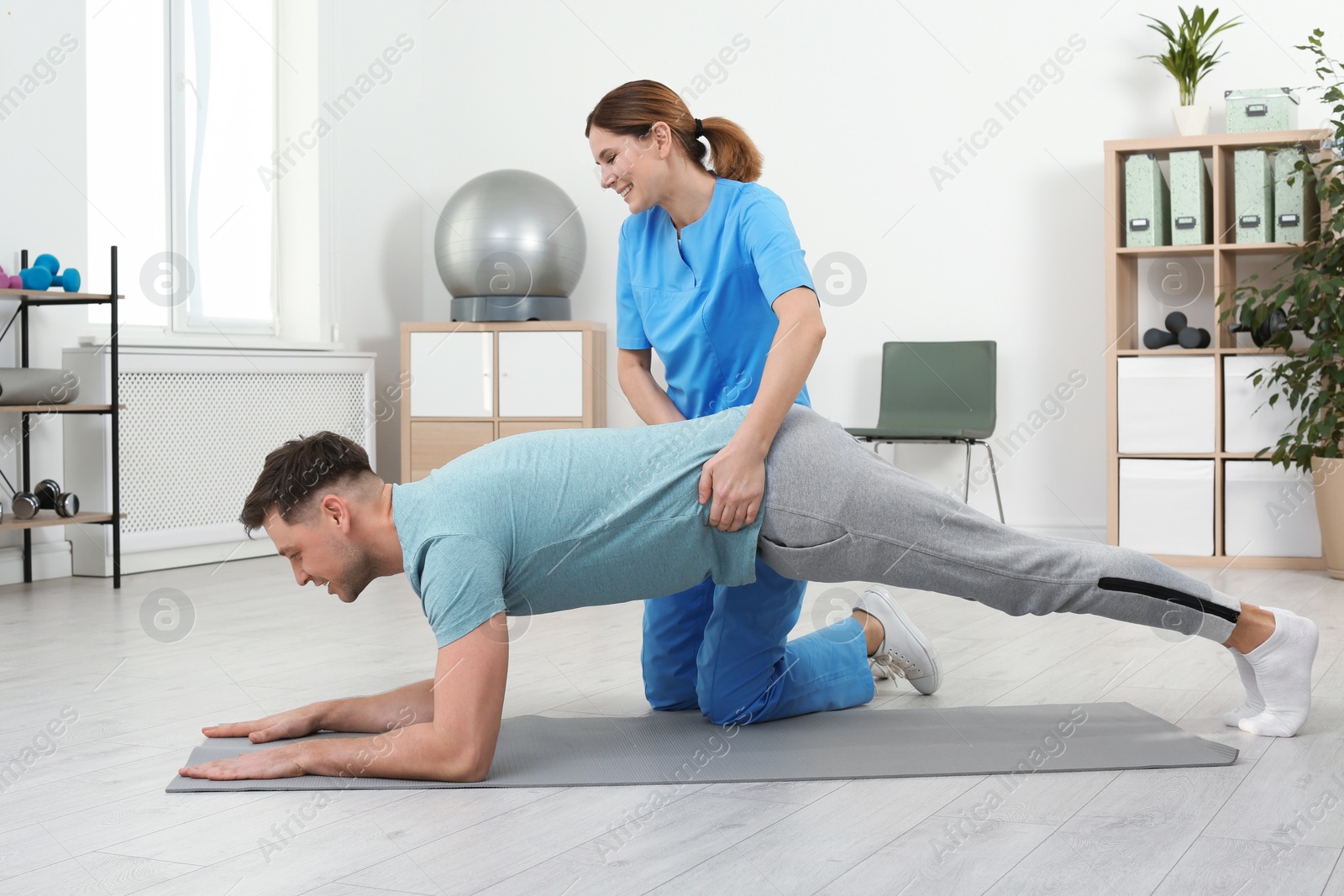 Photo of Physiotherapist working with patient in clinic. Rehabilitation therapy