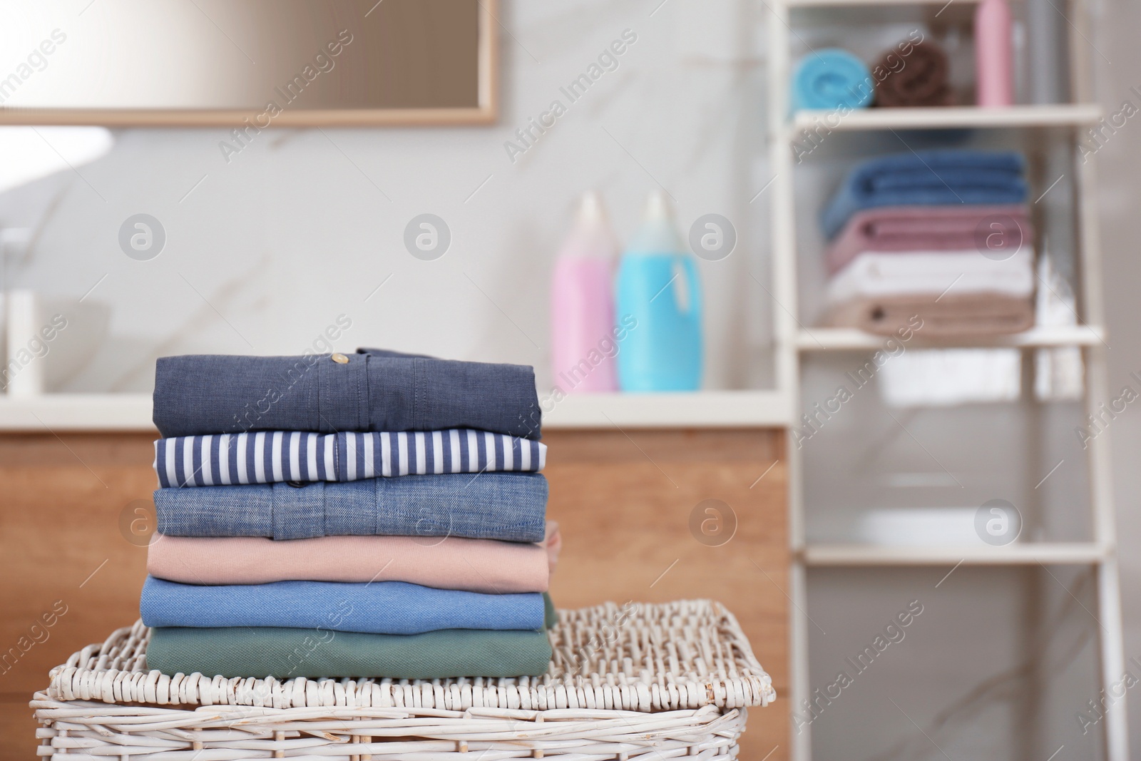 Photo of Stack of fresh laundry on basket in bathroom. Space for text
