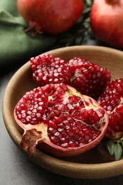 Cut fresh pomegranate and green leaves on grey table, closeup