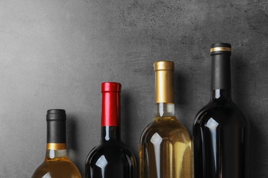 Photo of Bottles with delicious wine on grey background, top view