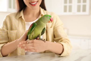 Young woman with Alexandrine parakeet indoors, closeup. Cute pet