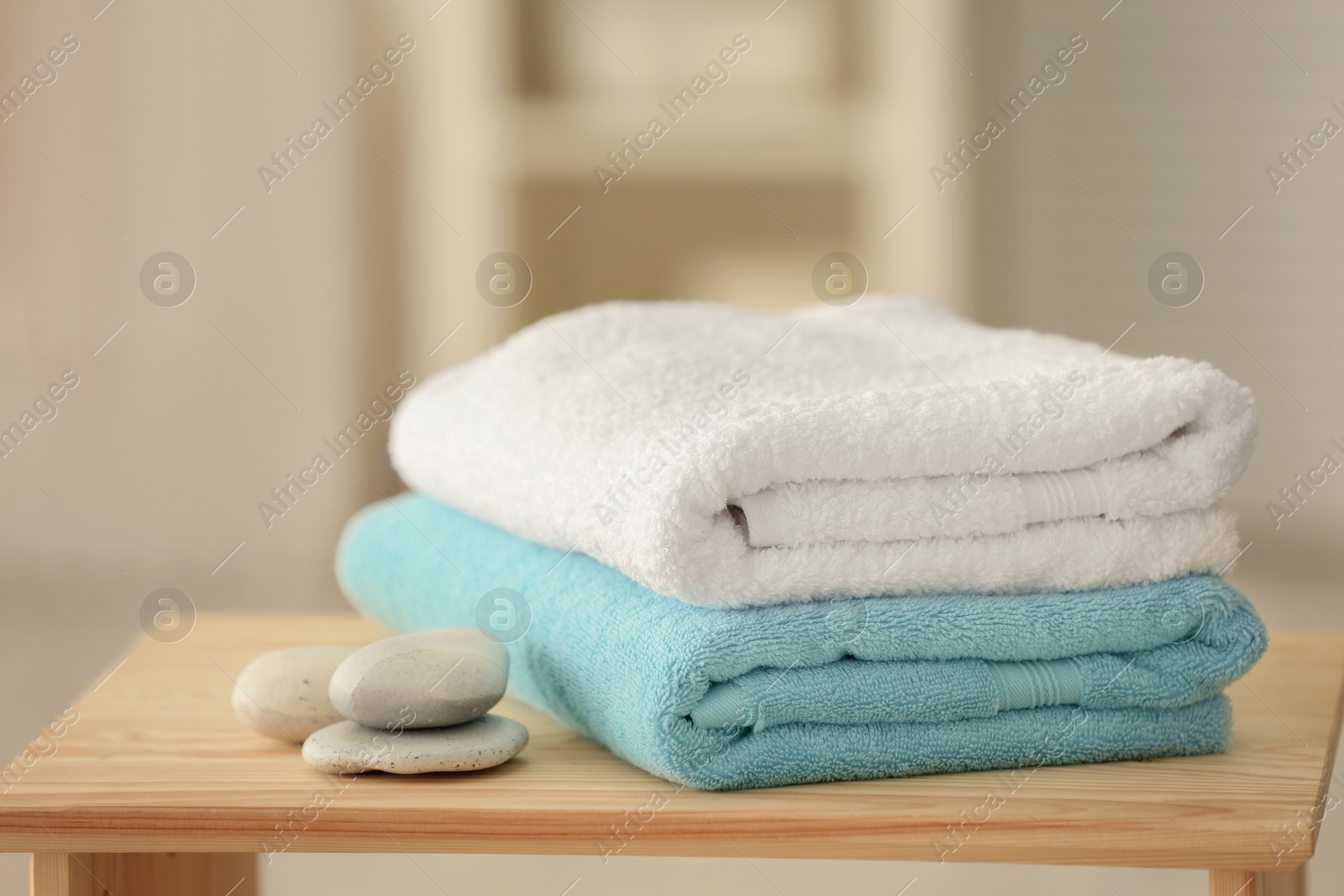 Photo of Clean towels and stones on table against blurred background