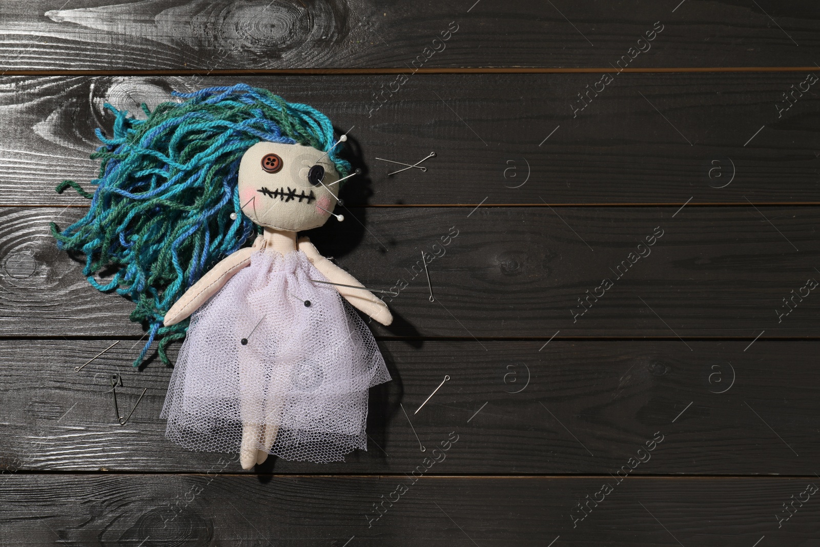 Photo of Female voodoo doll with pins on wooden background, flat lay. Space for text