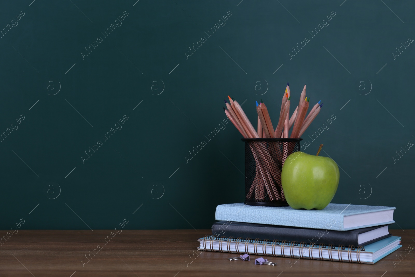 Photo of Composition with stationery and apple on table near chalkboard, space for text. Doing homework