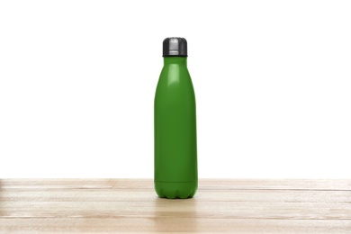 Photo of Stylish thermo bottle on wooden table against white background