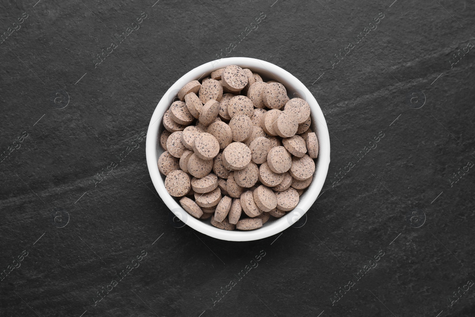 Photo of Brewer's yeast tablets in bowl on black table, top view