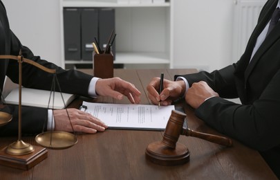Photo of Law and justice. Lawyers working with documents at wooden table in office, closeup