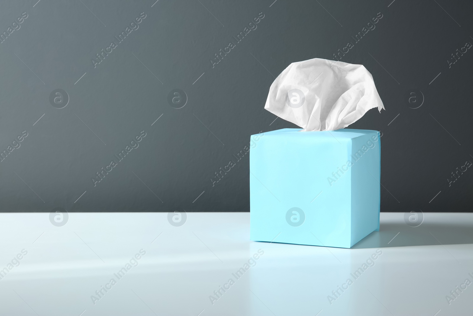 Photo of Box with paper tissues on white table. Space for text