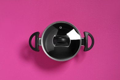 Empty pot with glass lid on dark pink background, top view