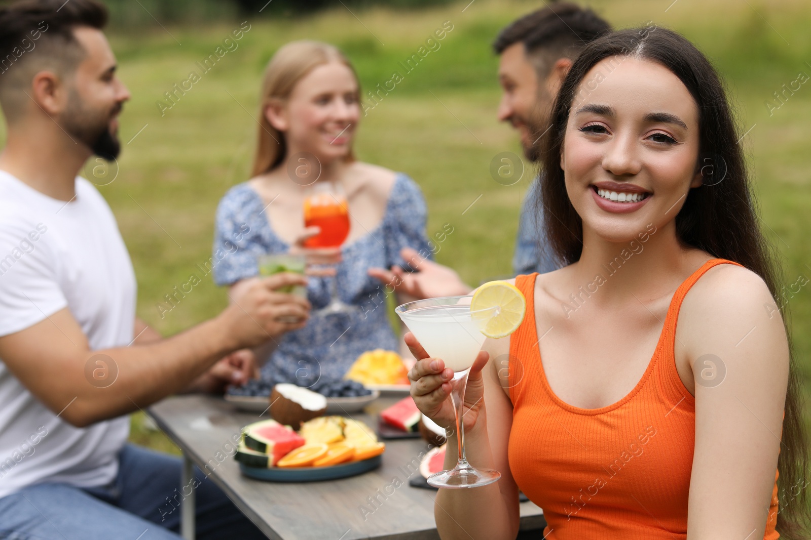 Photo of Friends having cocktail party outdoors. Happy woman with glass of drink, selective focus