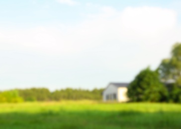 Photo of Blurred view of landscape with meadow and building on sunny day