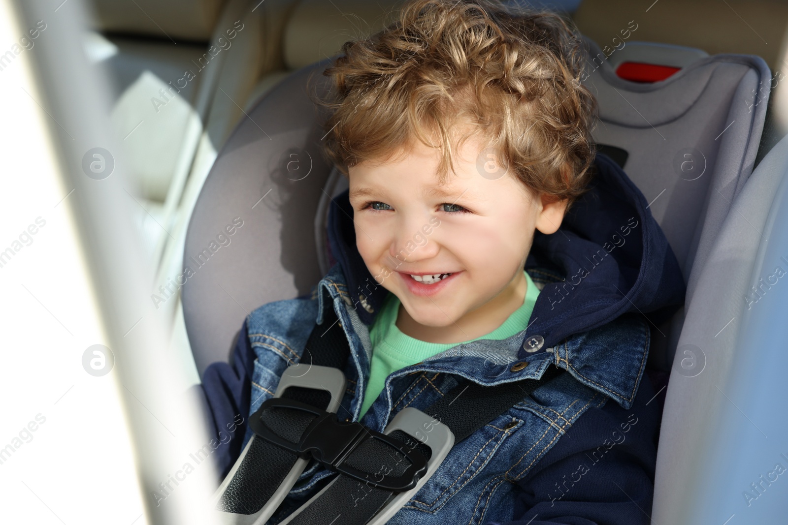 Photo of Cute little boy sitting in child safety seat inside car