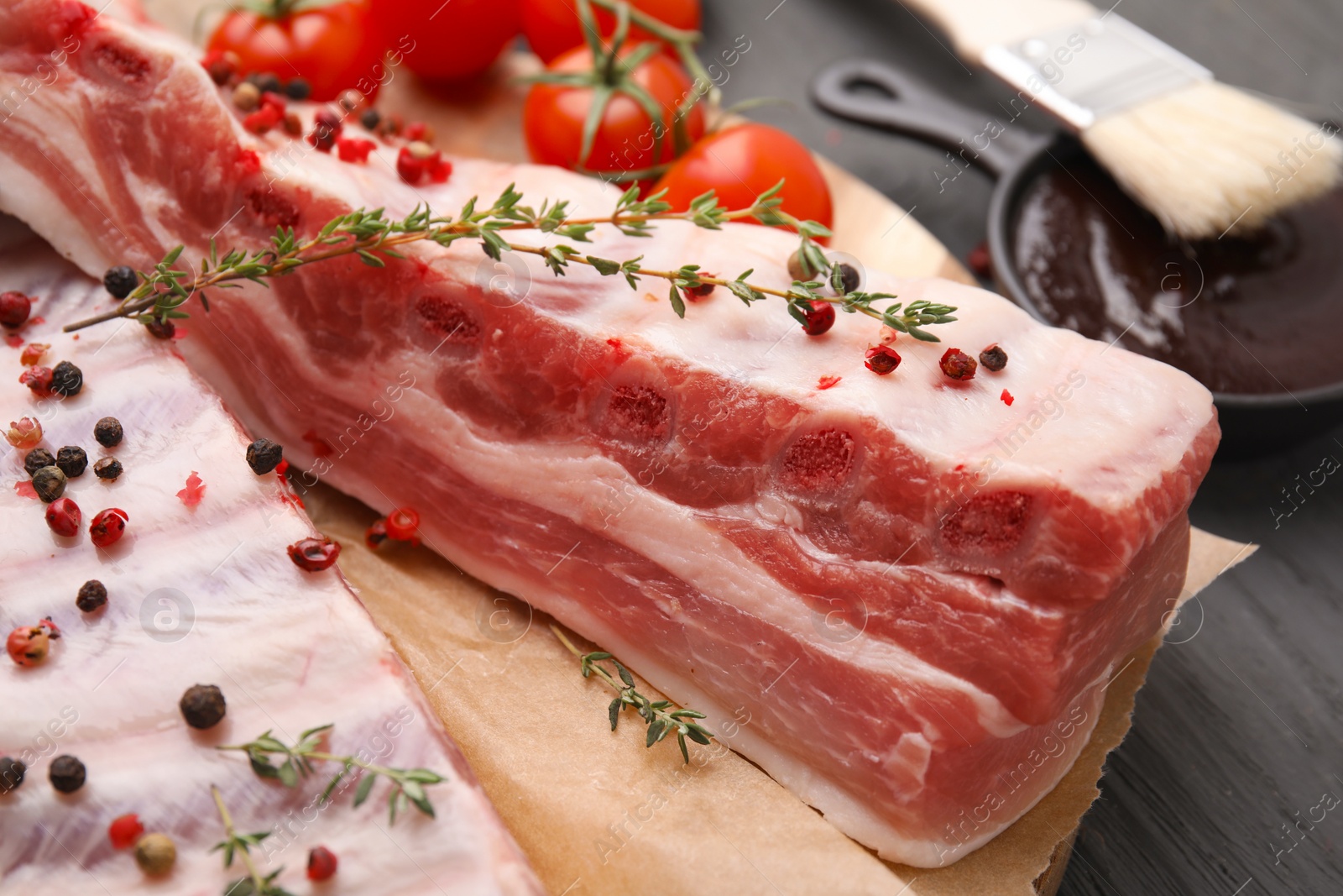 Photo of Raw pork ribs with thyme and peppercorns on table, closeup