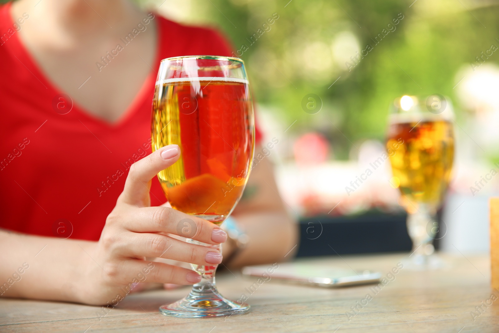 Photo of Young woman with glass of cold beer at table, closeup
