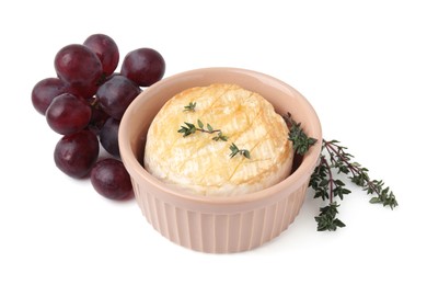 Photo of Tasty baked camembert in bowl, grapes and thyme on white background