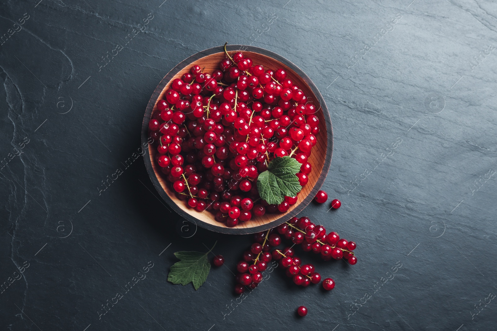 Photo of Delicious red currants on black slate table, flat lay