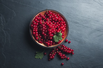 Photo of Delicious red currants on black slate table, flat lay
