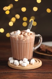 Cup of aromatic hot chocolate with marshmallows and cocoa powder on wooden table