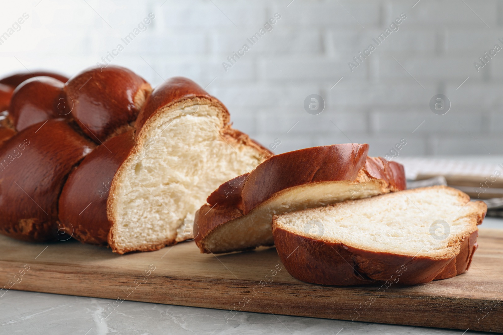 Photo of Cut homemade braided bread on grey table, closeup. Traditional Shabbat challah