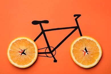 Photo of Drawn bicycle with orange slices instead of wheels on coral background, top view