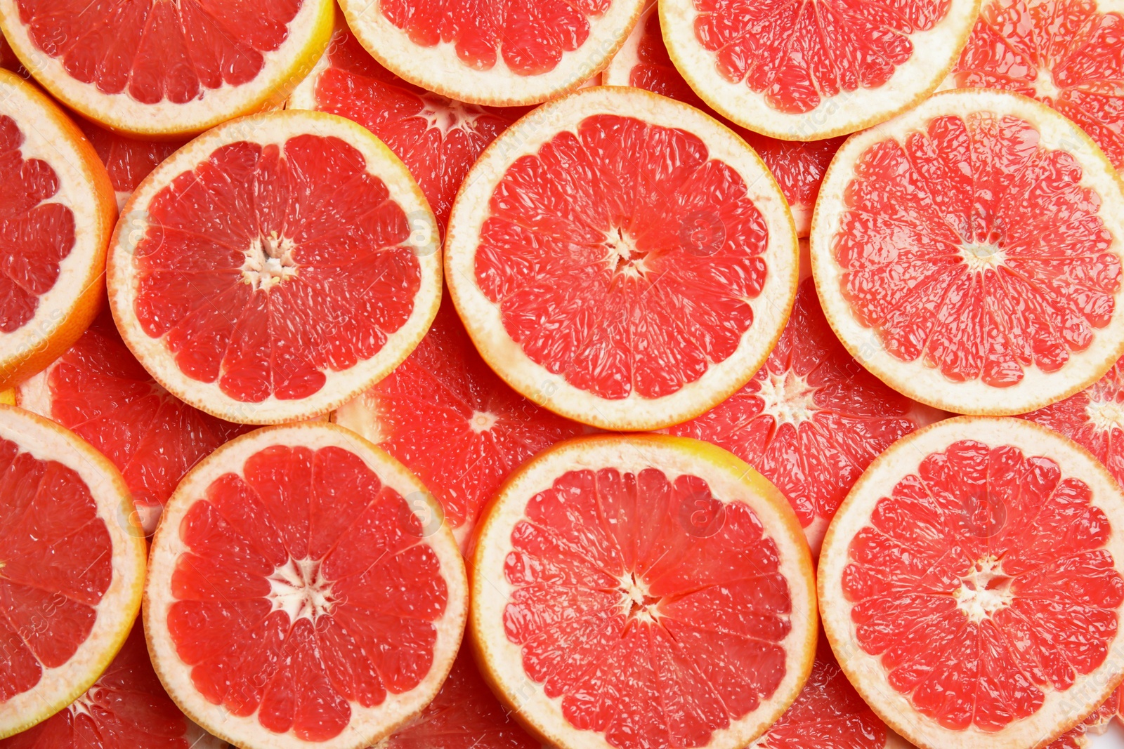 Photo of Many sliced fresh grapefruits as background, top view