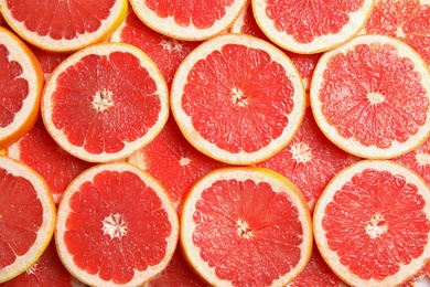 Many sliced fresh grapefruits as background, top view