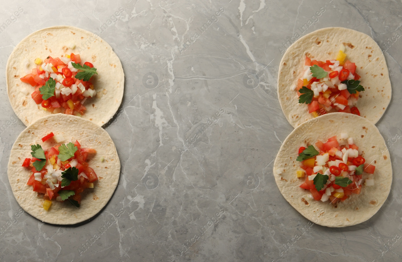 Photo of Delicious tacos with vegetables and parsley on grey marble table, top view. Space for text