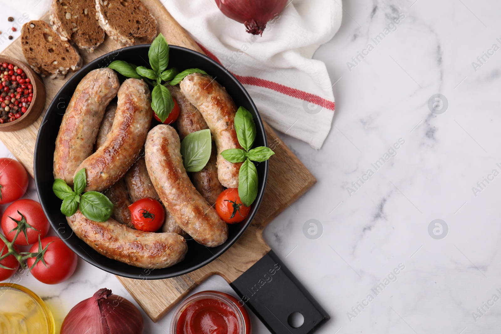 Photo of Flat lay composition with tasty homemade sausages, basil leaves and tomatoes in bowl on white marble table. Space for text