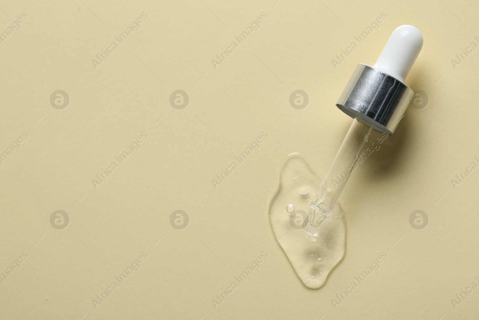 Photo of Pipette with cosmetic serum on beige background, top view. Space for text
