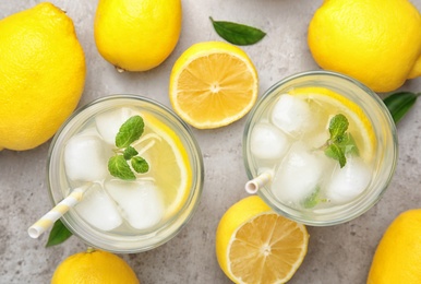 Cool freshly made lemonade and fruits on grey table, flat lay