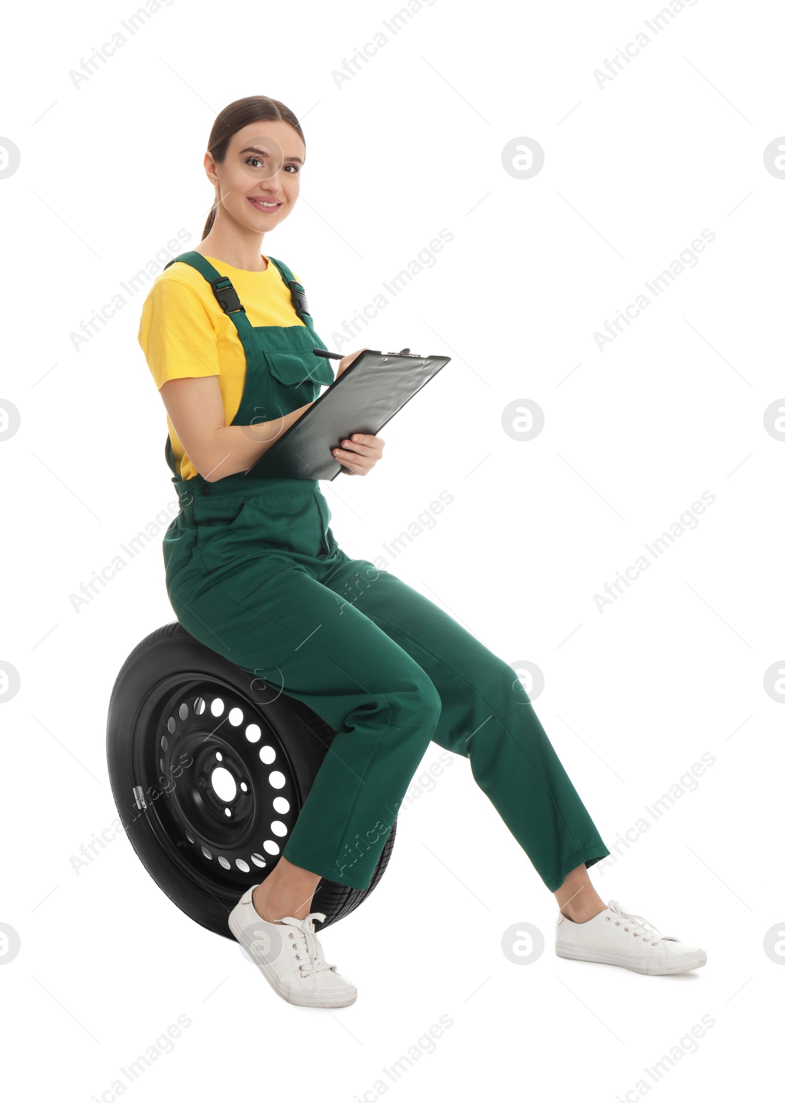 Photo of Professional auto mechanic with wheel and clipboard on white background