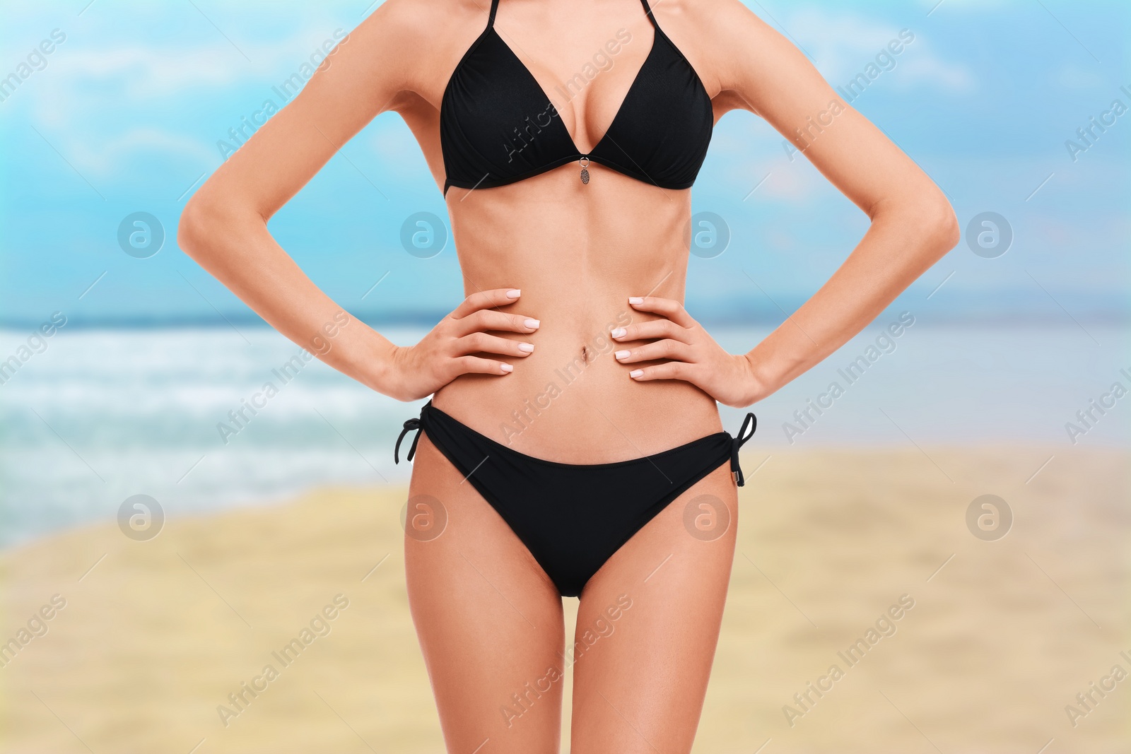 Image of Woman in stylish black bikini on sandy beach near sea, closeup