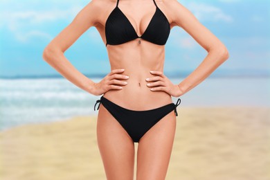 Image of Woman in stylish black bikini on sandy beach near sea, closeup