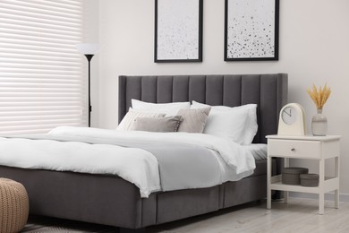 Stylish bedroom interior with large bed, bedside table and lamp