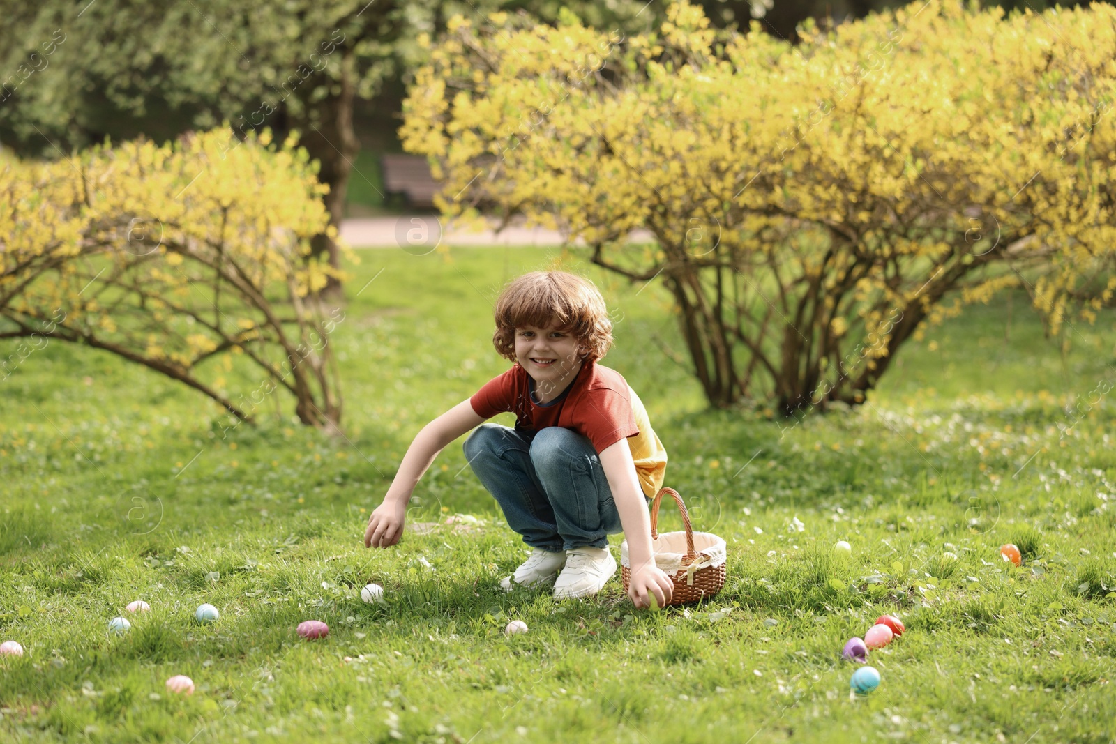 Photo of Easter celebration. Cute little boy hunting eggs outdoors