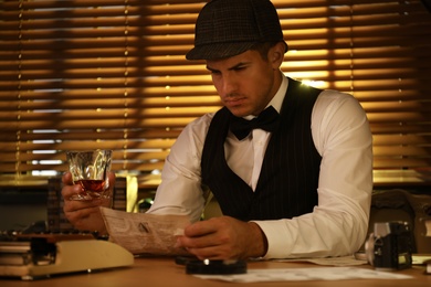 Old fashioned detective with drink working at table in office